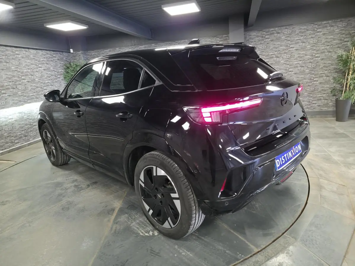 Vue 3/4 arrière droite de l'Opel Mokka-e 2025 noire avec feux arrière LED et jantes alliage 18 pouces.
