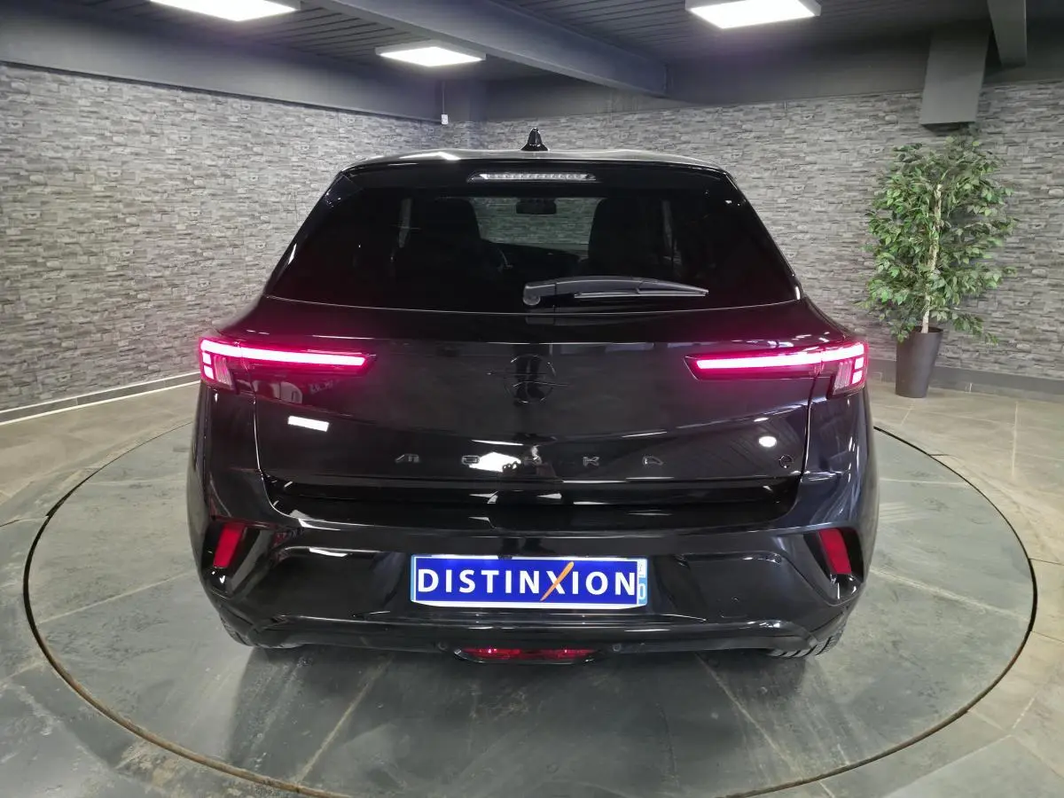 Vue arrière d'un Opel Mokka-e noir avec feux arrière LED allumés dans un showroom intérieur.