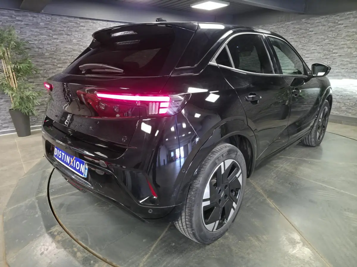 Vue 3/4 arrière droite de l'Opel Mokka-e noir avec feux arrière LED allumés et jantes alliage 18 pouces.