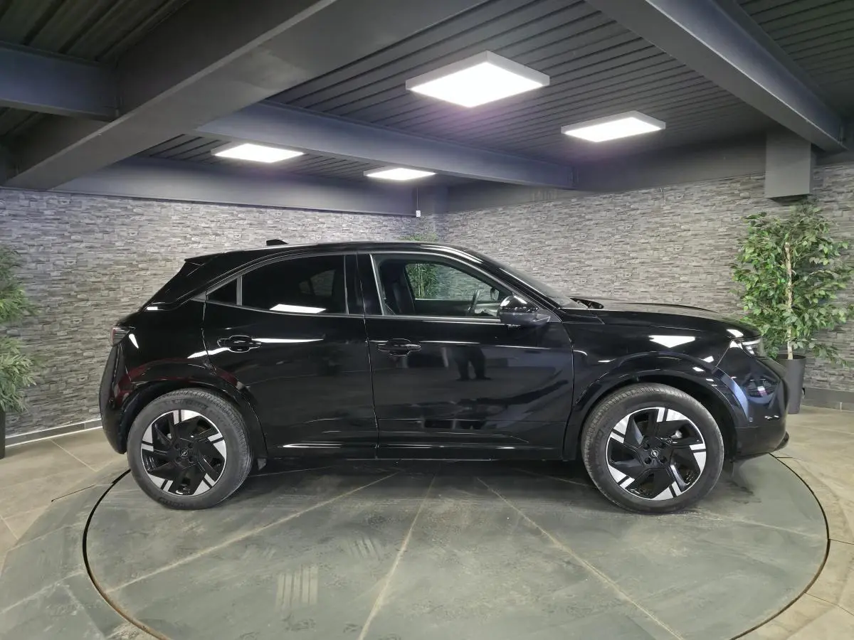 Opel Mokka-e noir vue de profil côté gauche, jantes alliage 18'' diamantées, intérieur visible à travers les vitres.