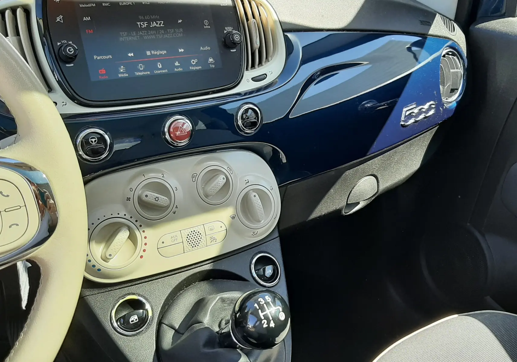 Vue intérieure côté passager de la FIAT 500 1.2 8V 69 Lounge 2018, tableau de bord bleu brillant et levier de vitesse manuel.