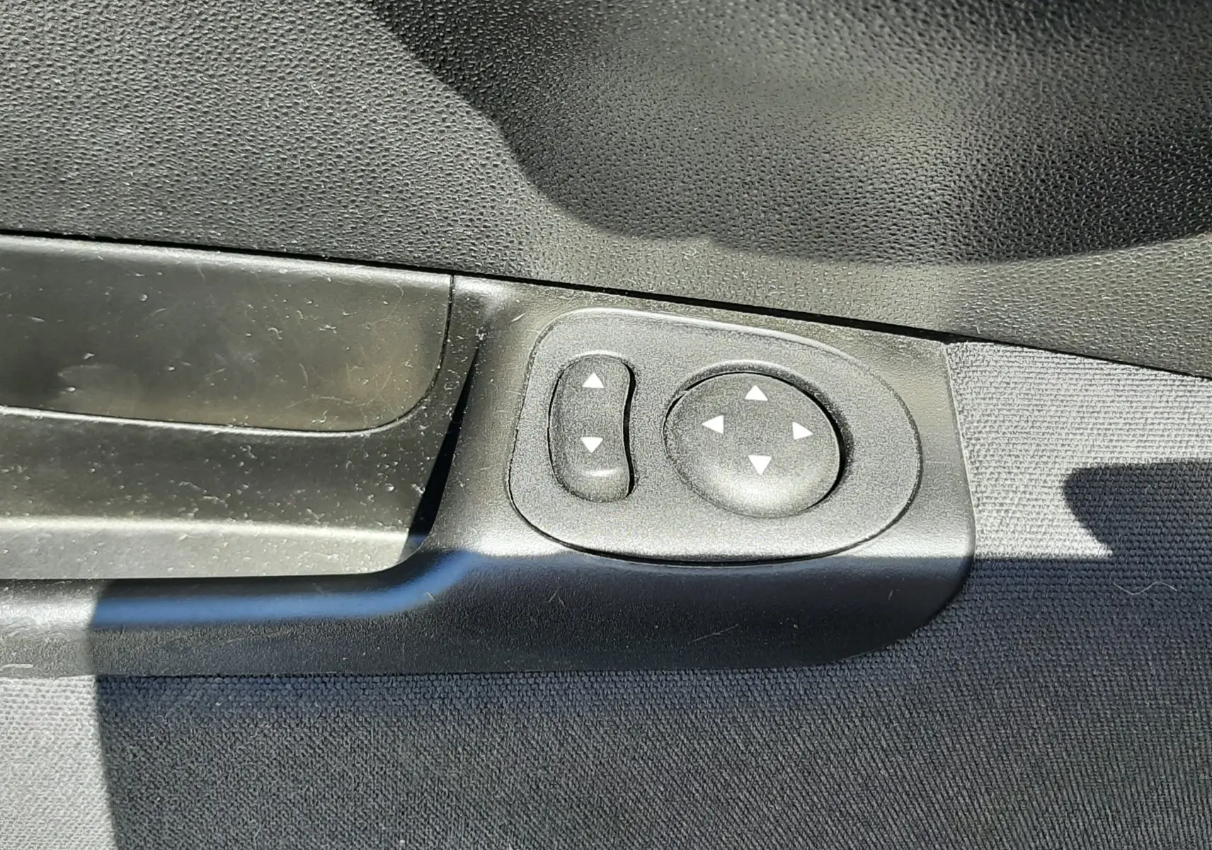 Gros plan sur les commandes électriques des rétroviseurs côté conducteur de la FIAT 500 bleue de 2018.