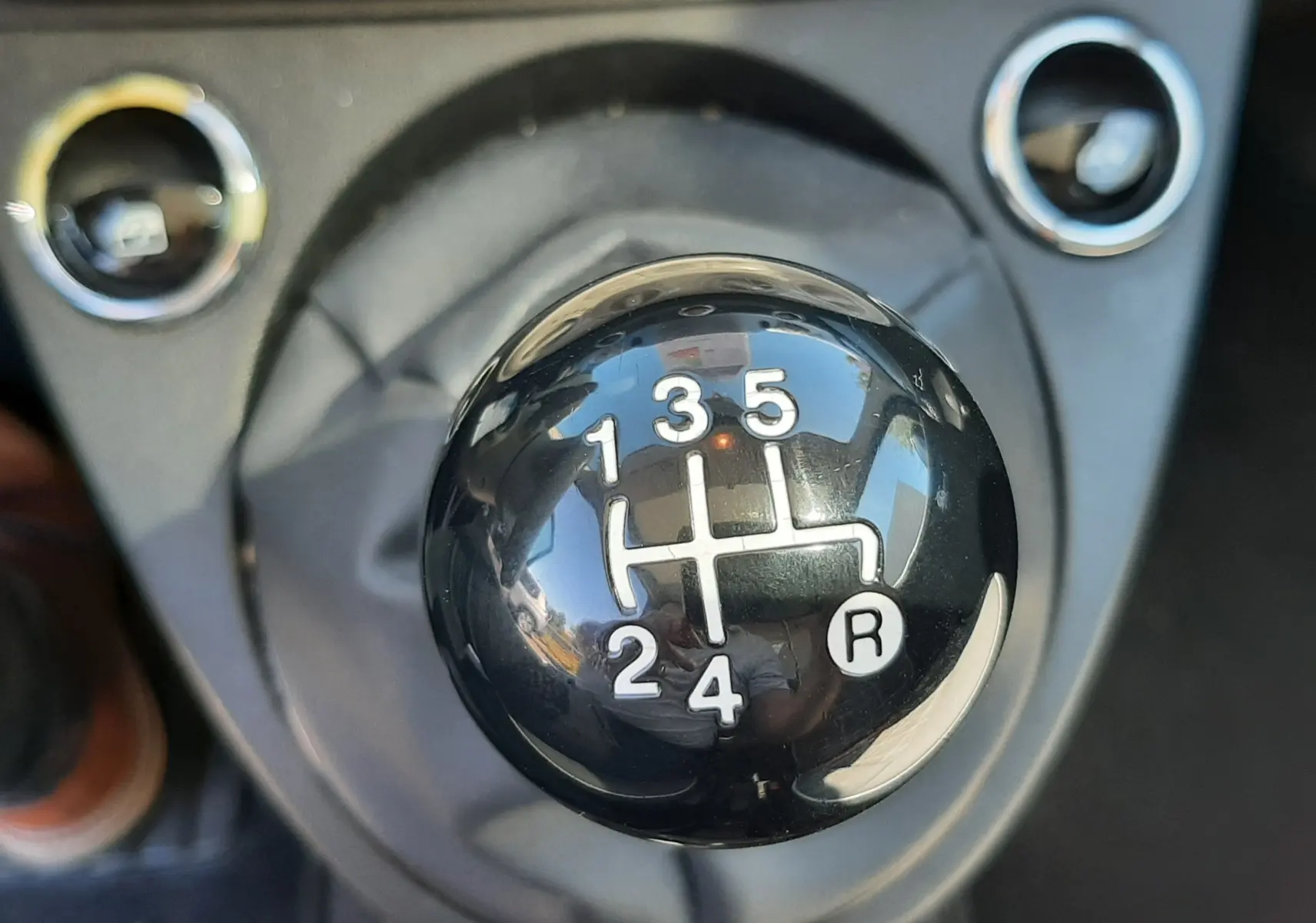 Gros plan sur le levier de vitesses manuel noir de la FIAT 500 bleu, montrant les positions des 5 rapports et de la marche arrière.
