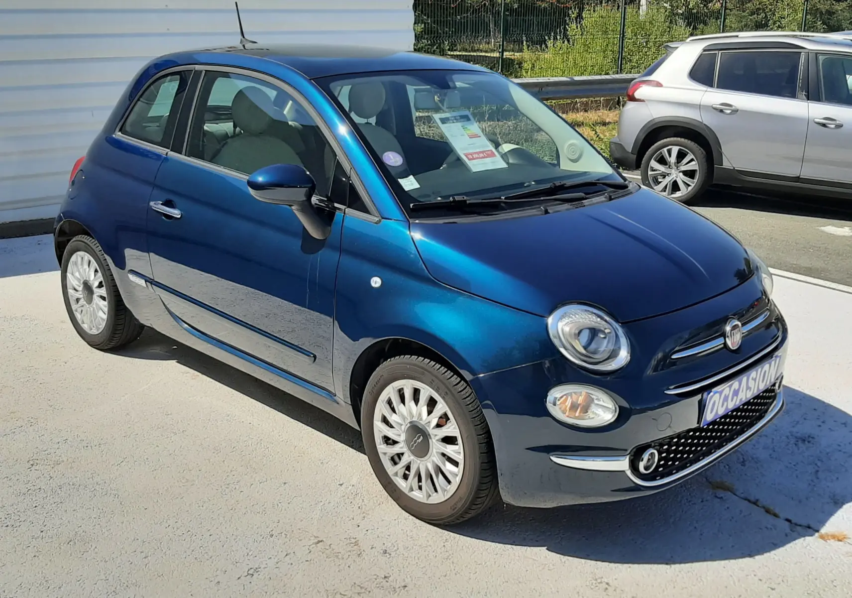 Fiat 500 bleu vue 3/4 avant droit, compacte avec jantes alliage et calandre chromée, stationnée en extérieur.