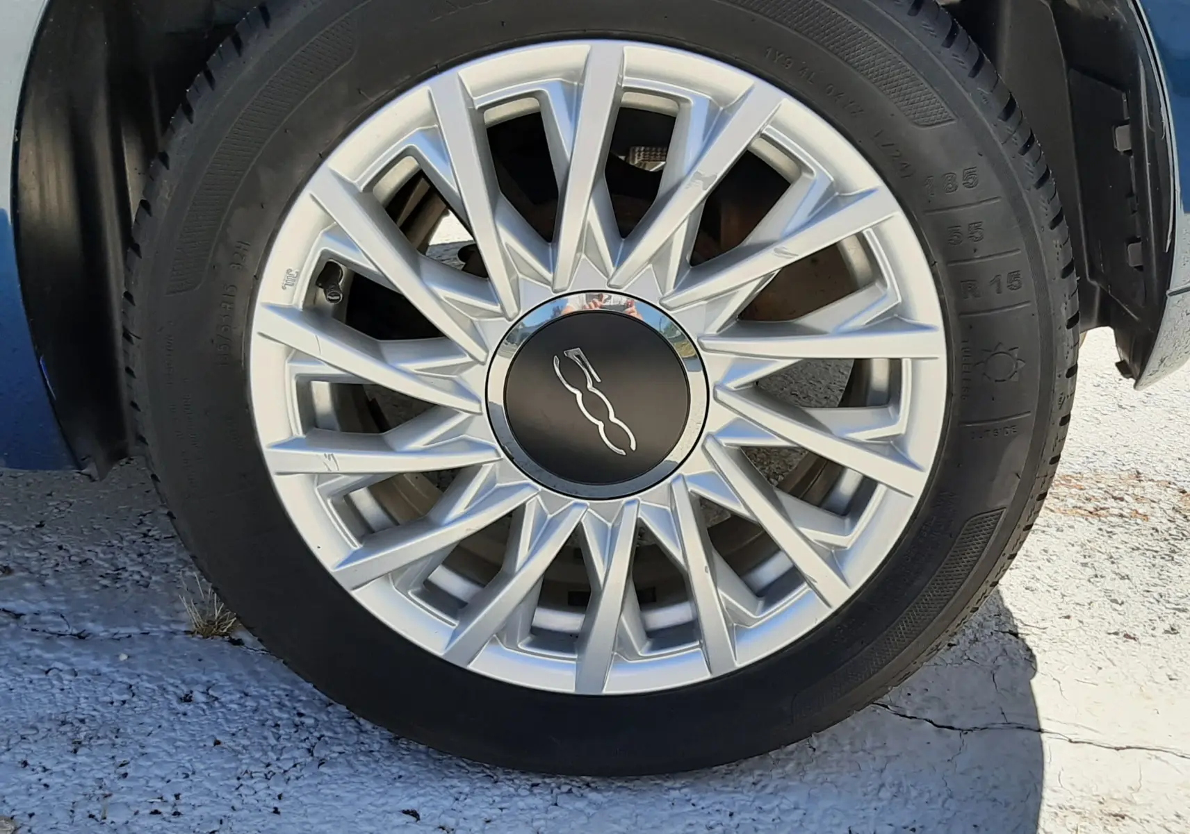 Gros plan sur la jante argentée d'une FIAT 500 bleu, mettant en valeur le logo central distinctif.