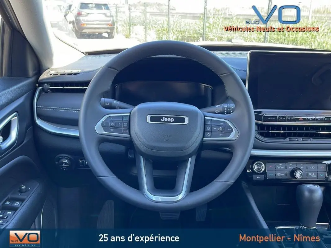 Vue intérieure centrée sur le volant Jeep noir et tableau de bord avec écran tactile du Compass blanc 2024.