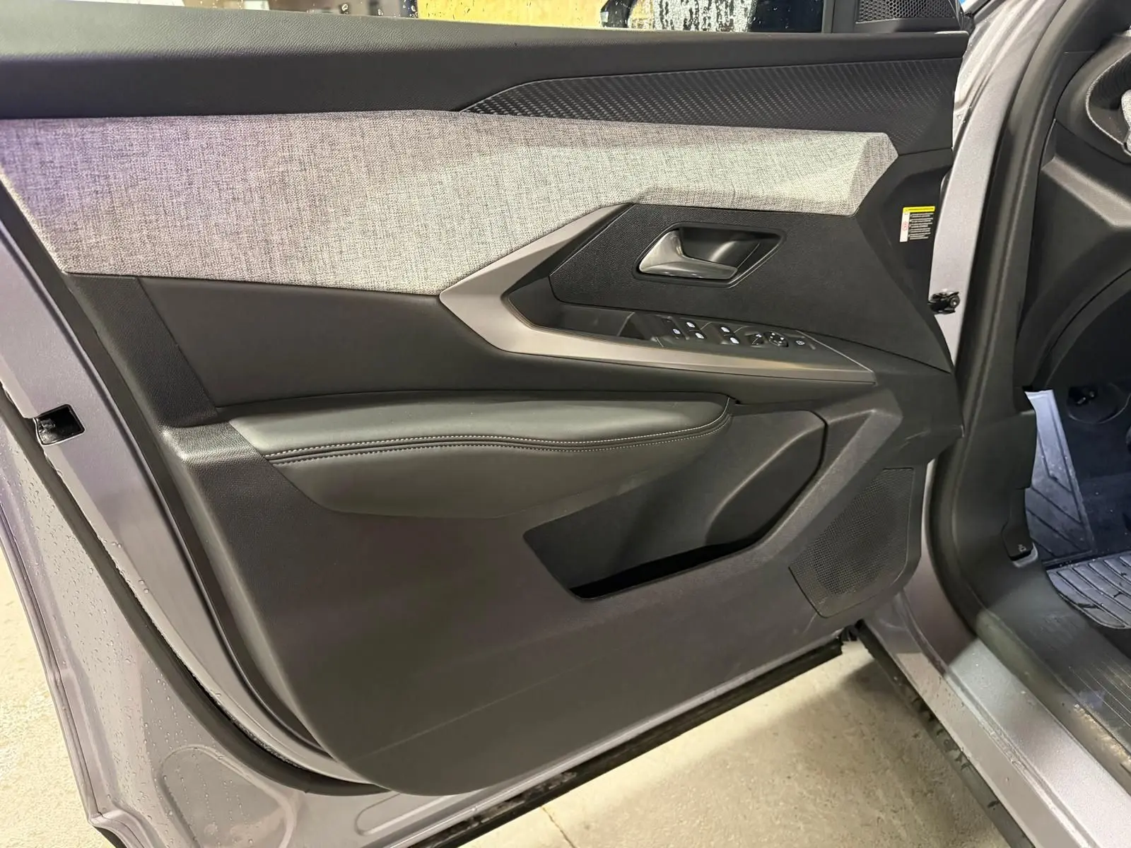 Vue rapprochée de la porte avant gauche grise du Peugeot 3008 1.2 Hybrid 136 Allure avec habillage tissu et commandes électriques.