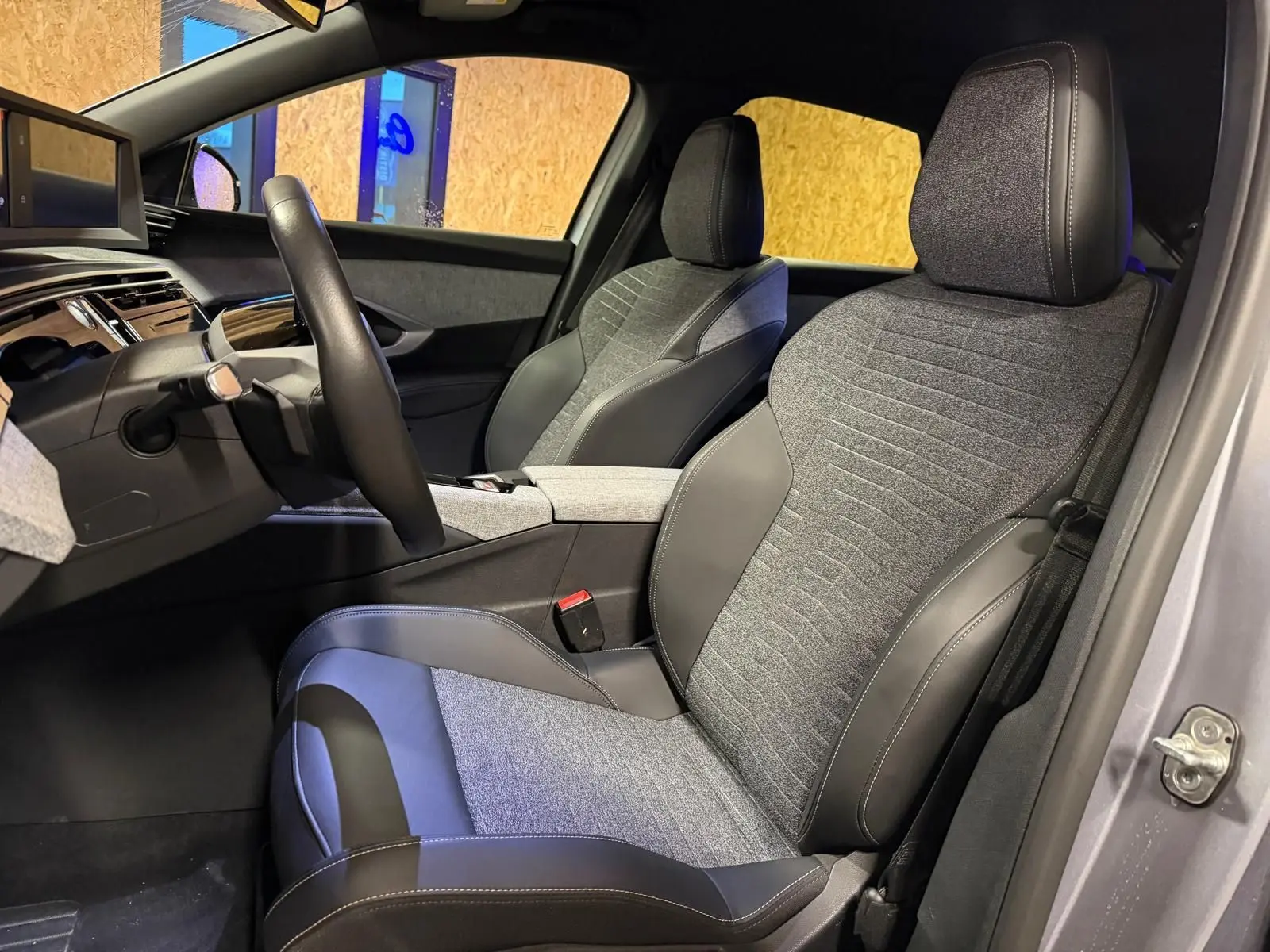 Vue intérieure côté conducteur du Peugeot 3008 1.2 Hybrid 136 Allure gris, sièges tissu et cuir gris foncé.