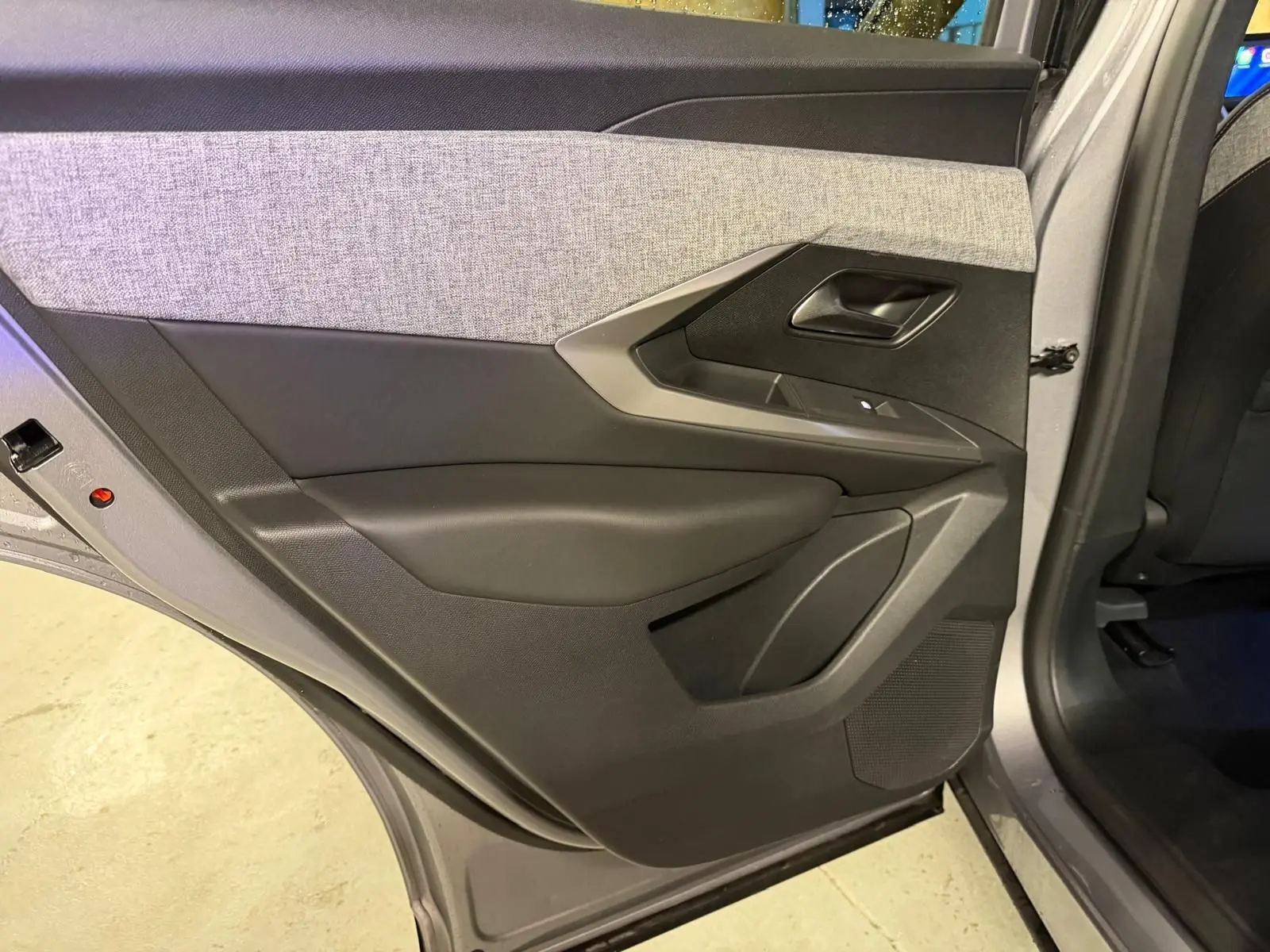 Vue intérieure de la porte arrière gauche grise du Peugeot 3008 1.2 Hybrid 136 Allure avec garniture tissu gris et plastique noir.