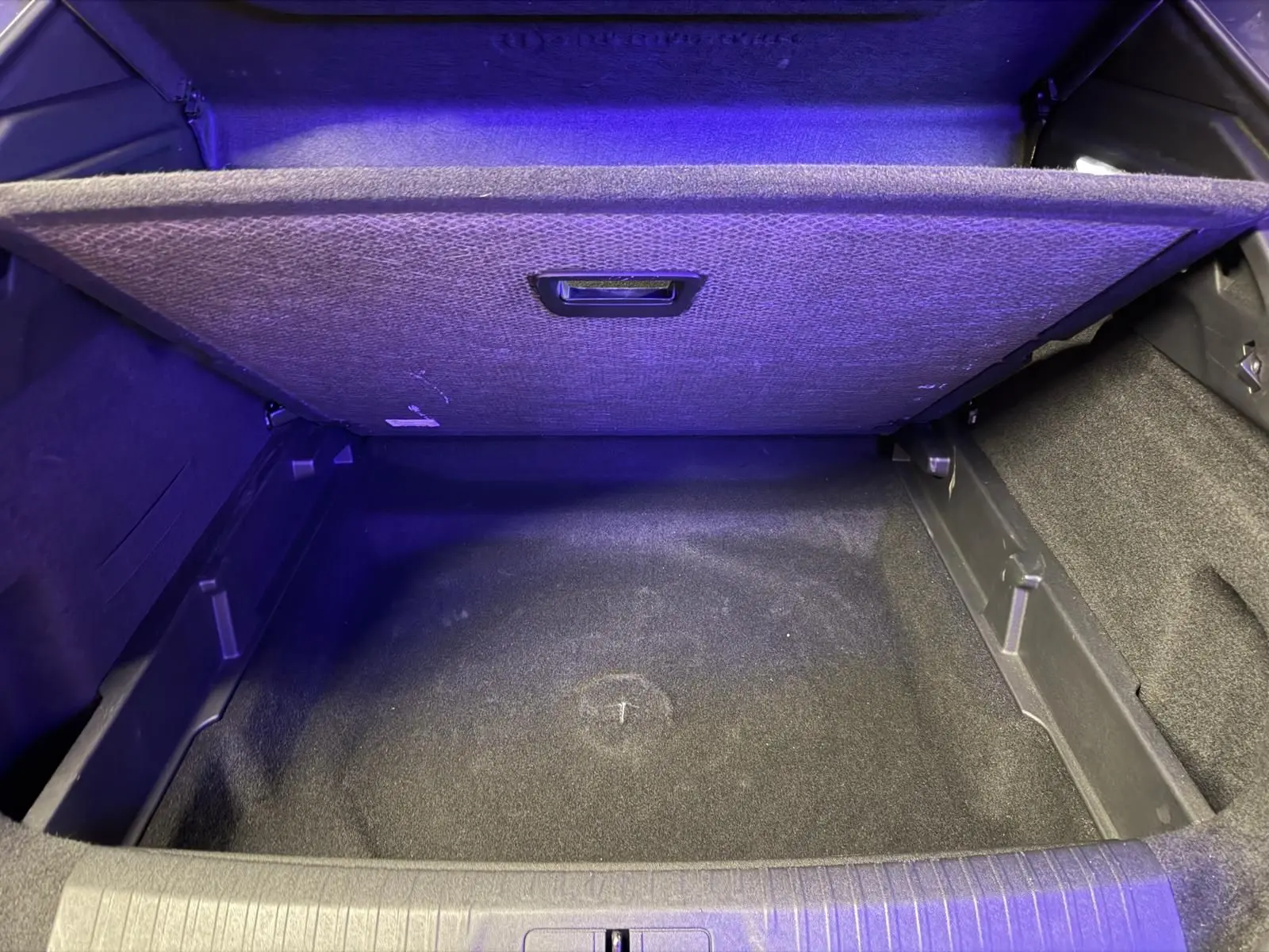 Coffre ouvert du Peugeot 3008 1.2 Hybrid 136 Allure gris, montrant le compartiment de rangement sous plancher.