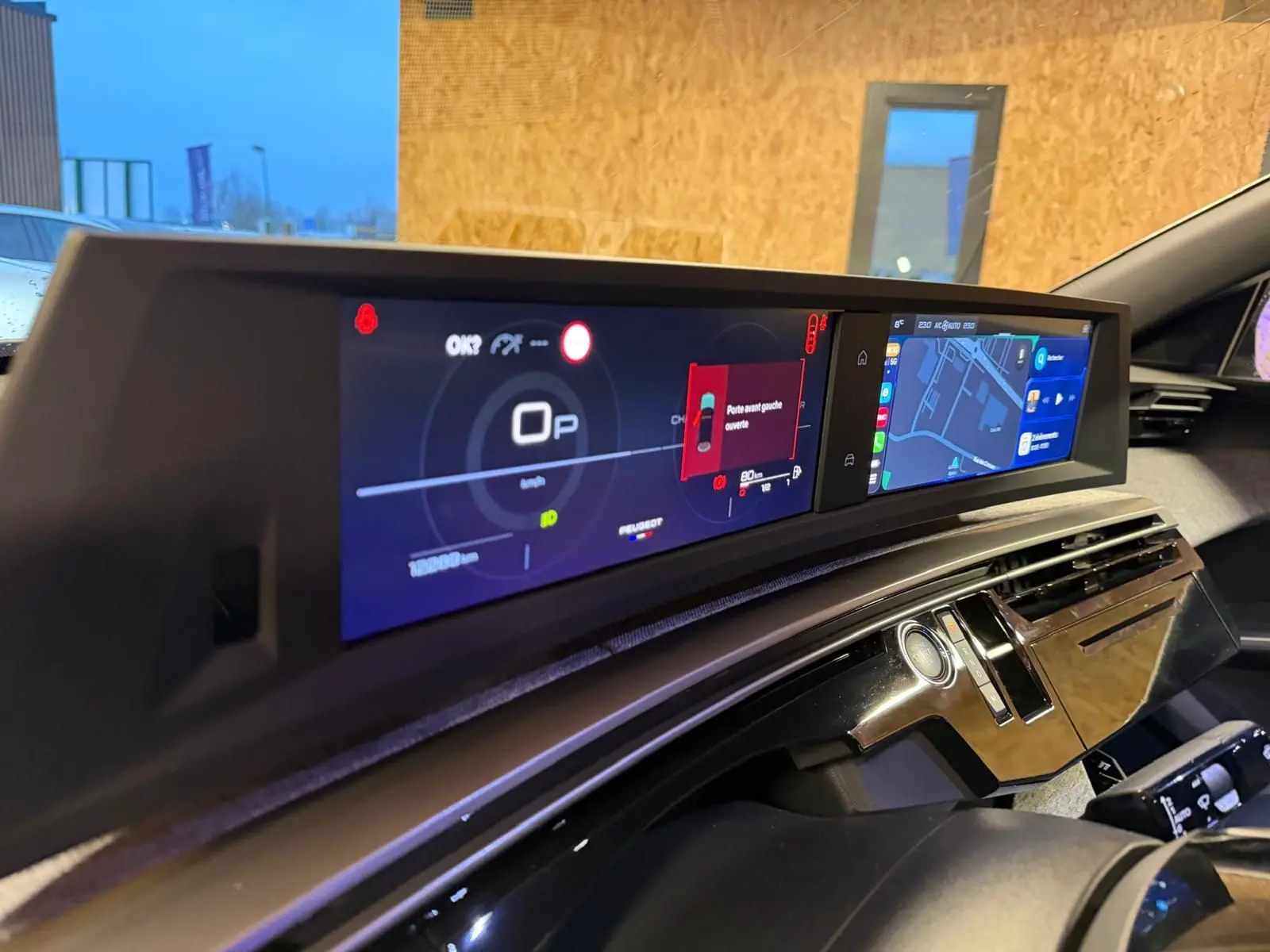 Vue rapprochée du tableau de bord numérique et écran central du Peugeot 3008 gris, affichant la navigation et alertes.