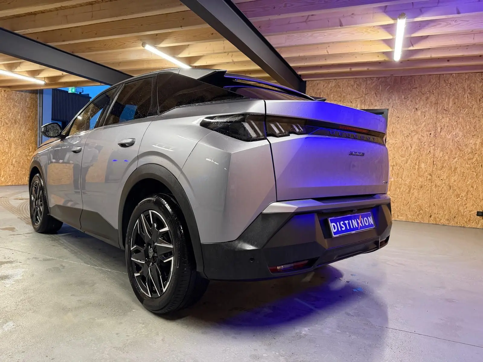 Vue 3/4 arrière droite du Peugeot 3008 gris hybride 2025 avec toit noir et jantes alliage distinctives.