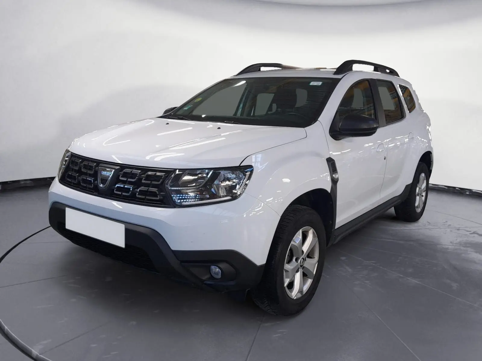 Dacia Duster blanc en 3/4 avant droit, SUV compact avec calandre noire et jantes alliage 16 pouces.