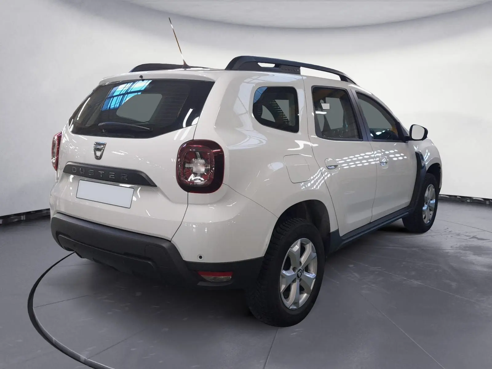 Vue arrière d'un Dacia Duster blanc 2021 avec grille de séparation visible à travers la lunette arrière.