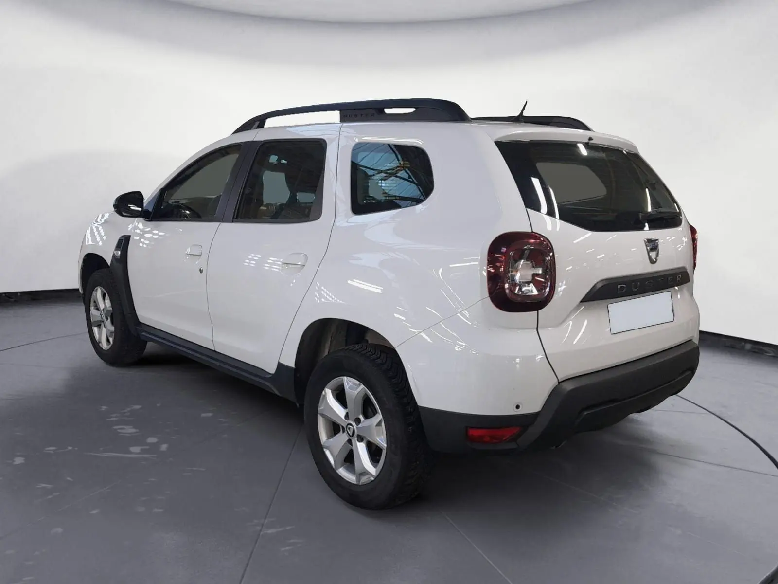 Profil côté gauche d’un Dacia Duster blanc 2021 avec jantes alliage et grille de séparation visible à l’arrière.