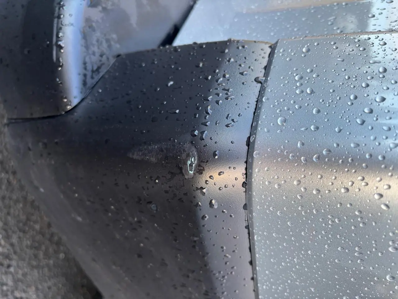 Gros plan sur l’arrière droit gris clair du Renault Trafic Fourgon avec gouttes de pluie visibles sur la carrosserie.