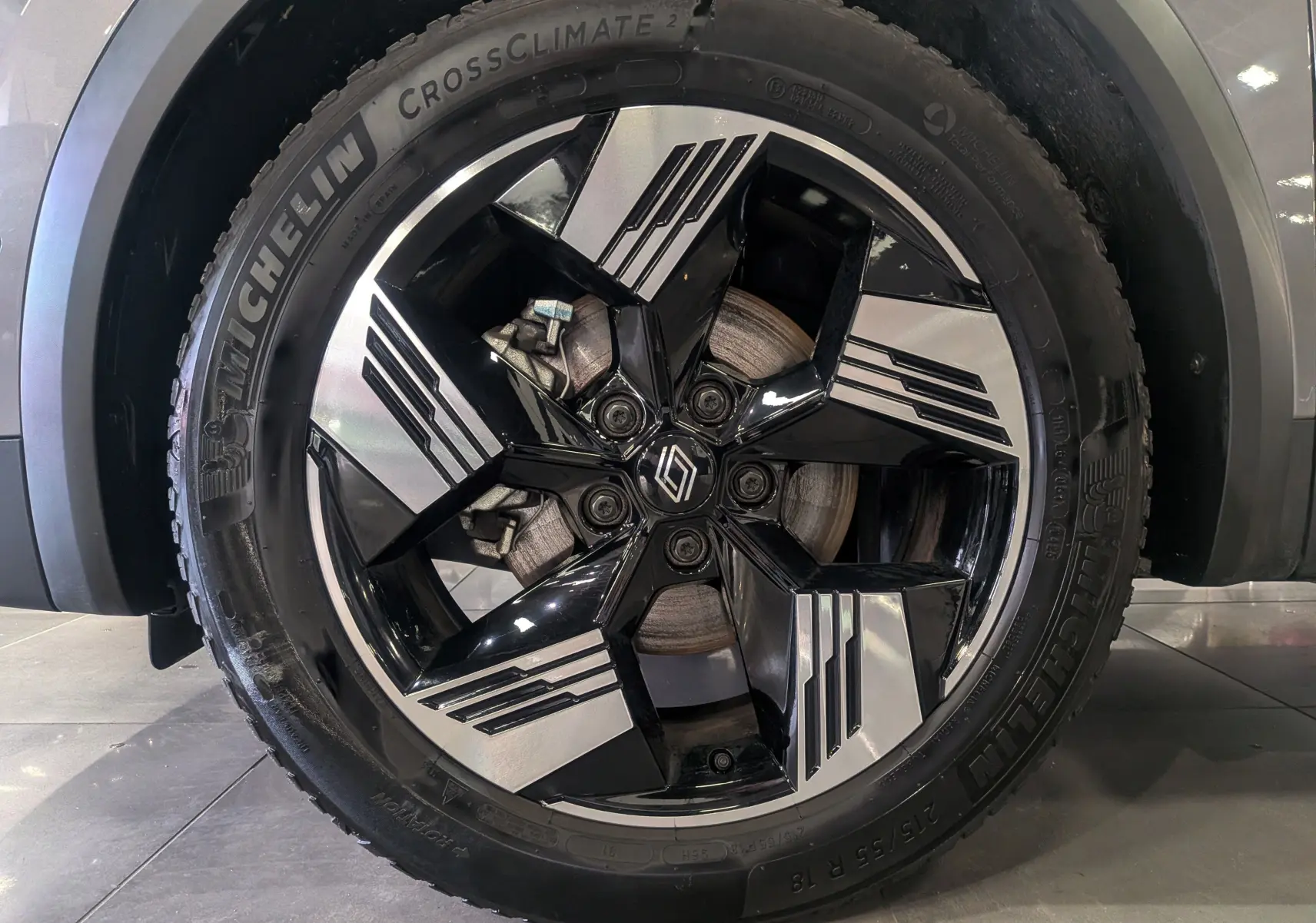 Gros plan sur la roue avant droite du Renault Symbioz gris Cassiopé, mettant en valeur la jante noire et argentée au design moderne.