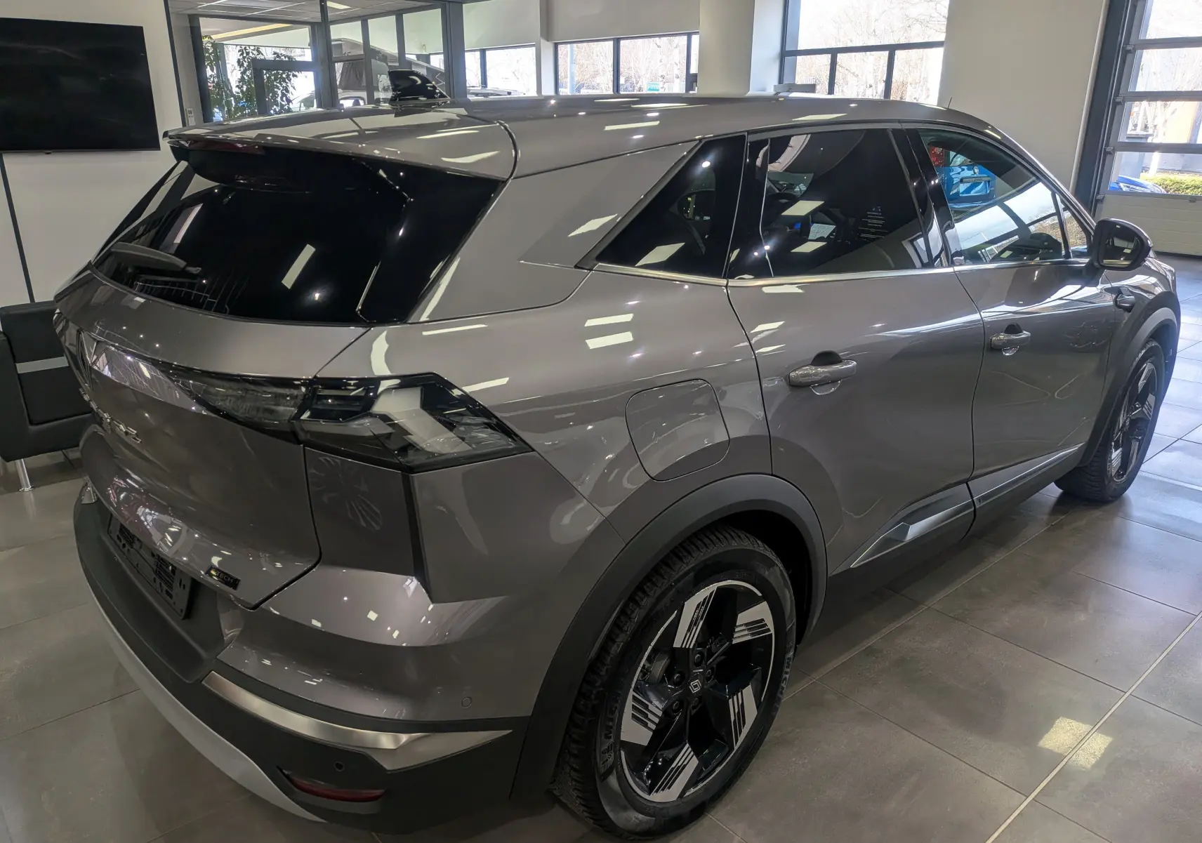 Vue 3/4 arrière droite du Renault SYMBIOZ E-TECH gris Cassiopé, avec jantes bi-ton et vitres teintées en showroom.