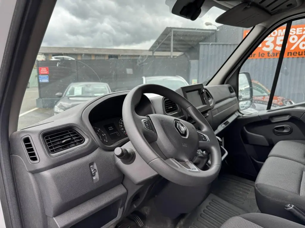 Vue intérieure côté conducteur du Renault Master blanc 2022, tableau de bord et volant avec logo Renault visibles.