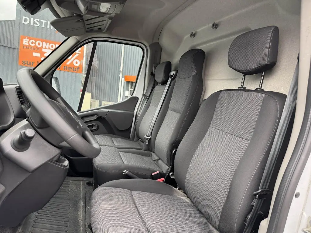 Vue intérieure côté conducteur du Renault Master blanc 2022, montrant la banquette 3 places en tissu gris et le volant noir.