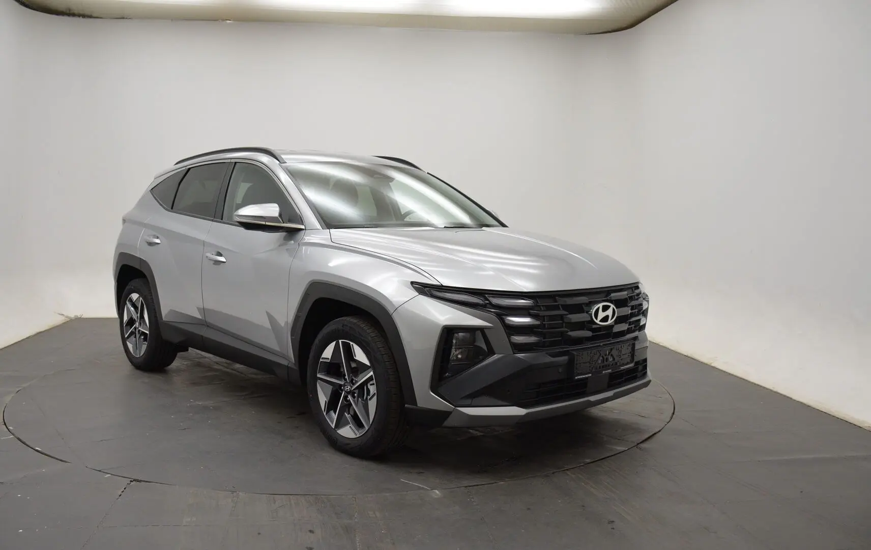 Vue frontale d'un Hyundai Tucson 2025 gris argenté avec calandre noire et feux LED intégrés.