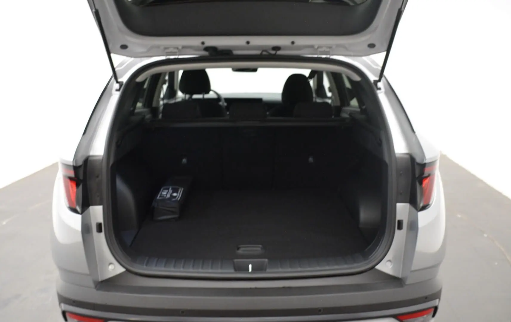 Vue arrière du Hyundai Tucson 2025 Shimmering Silver avec coffre ouvert et intérieur noir visible.