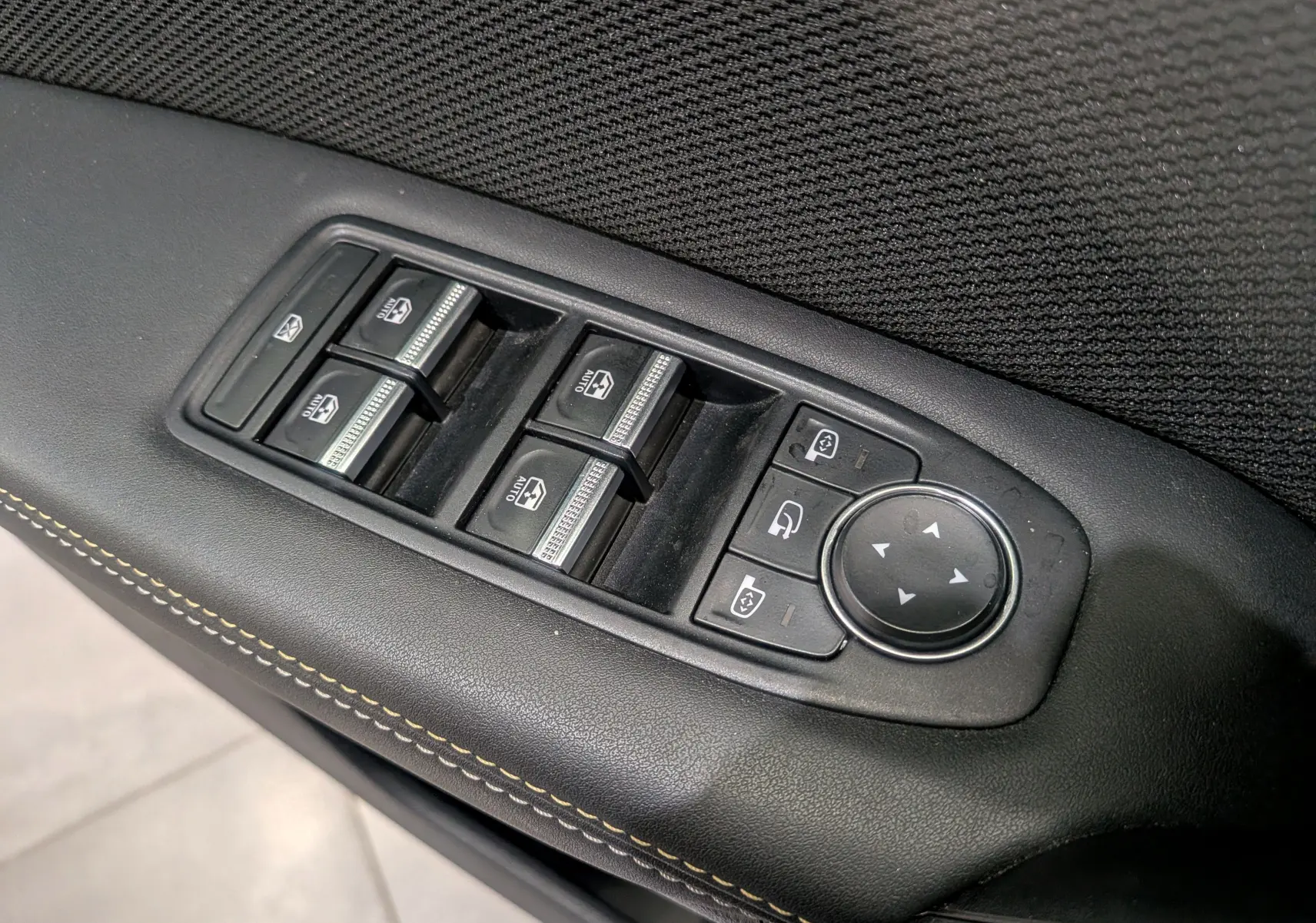 Gros plan sur les commandes des vitres et rétroviseurs côté conducteur du Renault Symbioz gris Cassiopé, finition Iconic.