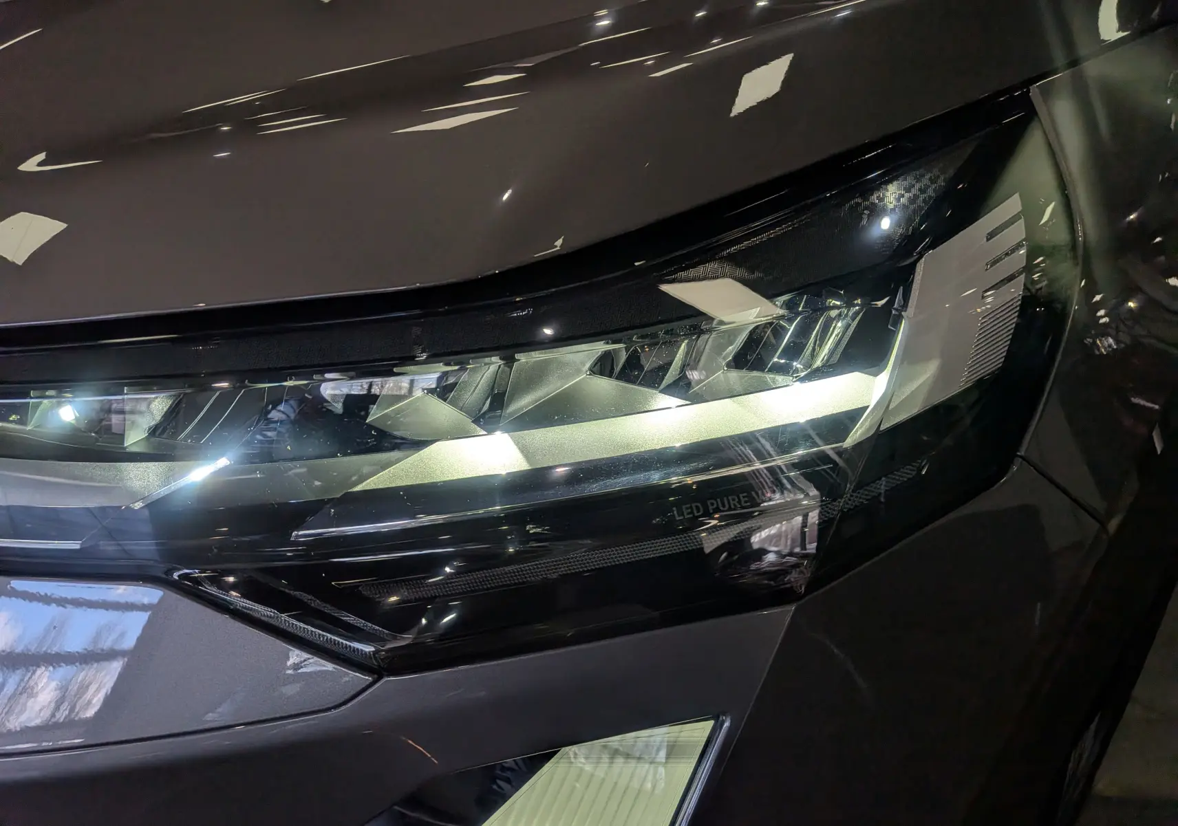 Gros plan sur le phare avant droit du Renault SYMBIOZ gris Cassiopé avec éclairage LED distinctif.