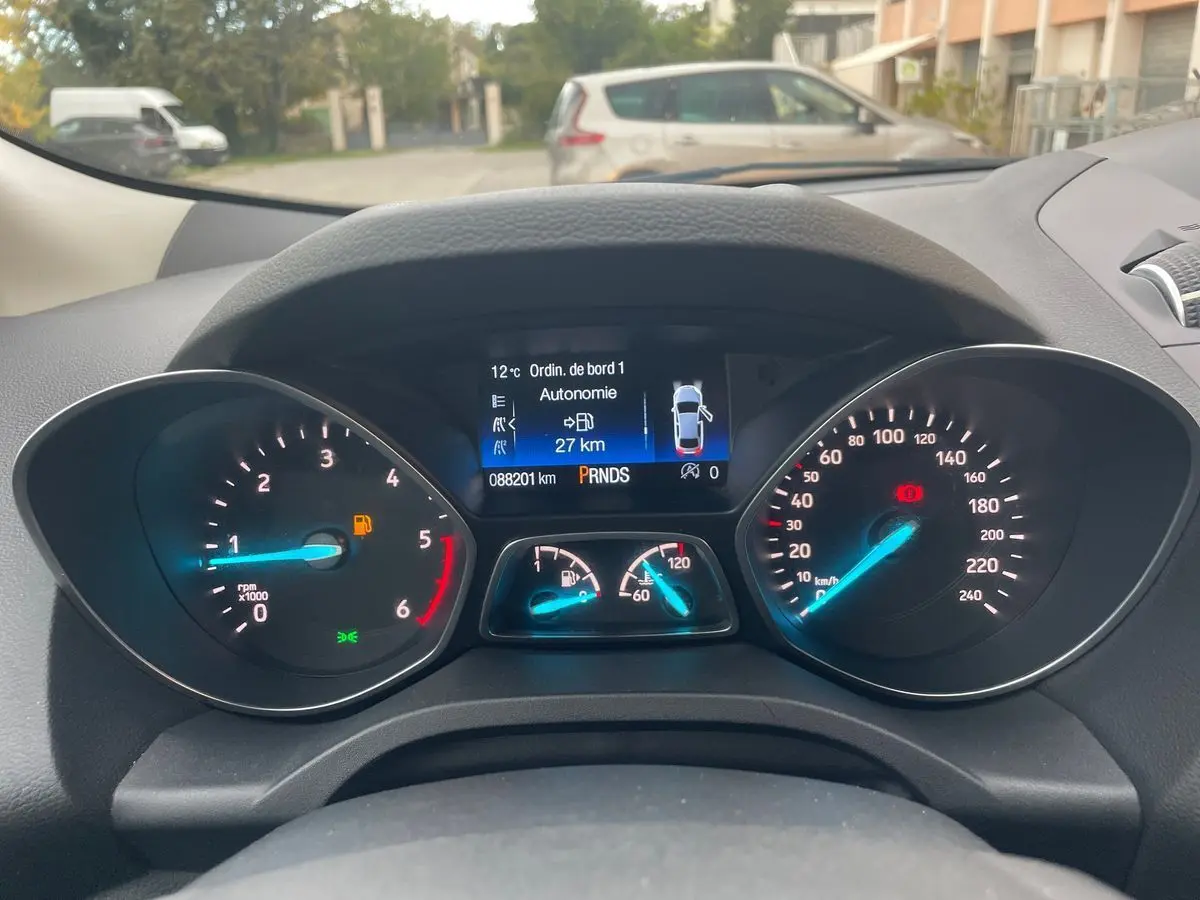 Vue rapprochée du tableau de bord du Ford Kuga gris 2017, affichant les compteurs et l'écran digital central.