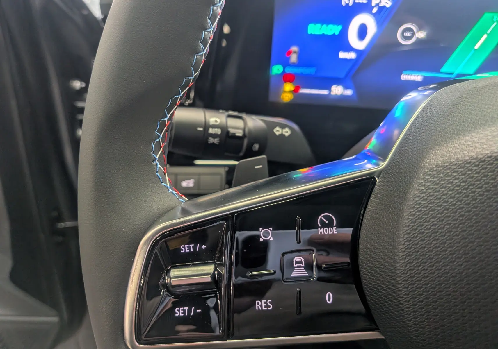 Gros plan sur la partie gauche du volant du Renault Rafale E-TECH 2025 avec commandes de régulateur et tableau de bord numérique en arrière-plan.