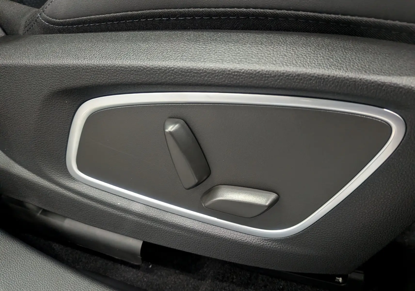 Gros plan sur les commandes de réglage électrique du siège avant en cuir noir du Renault Rafale gris Schiste Satin.