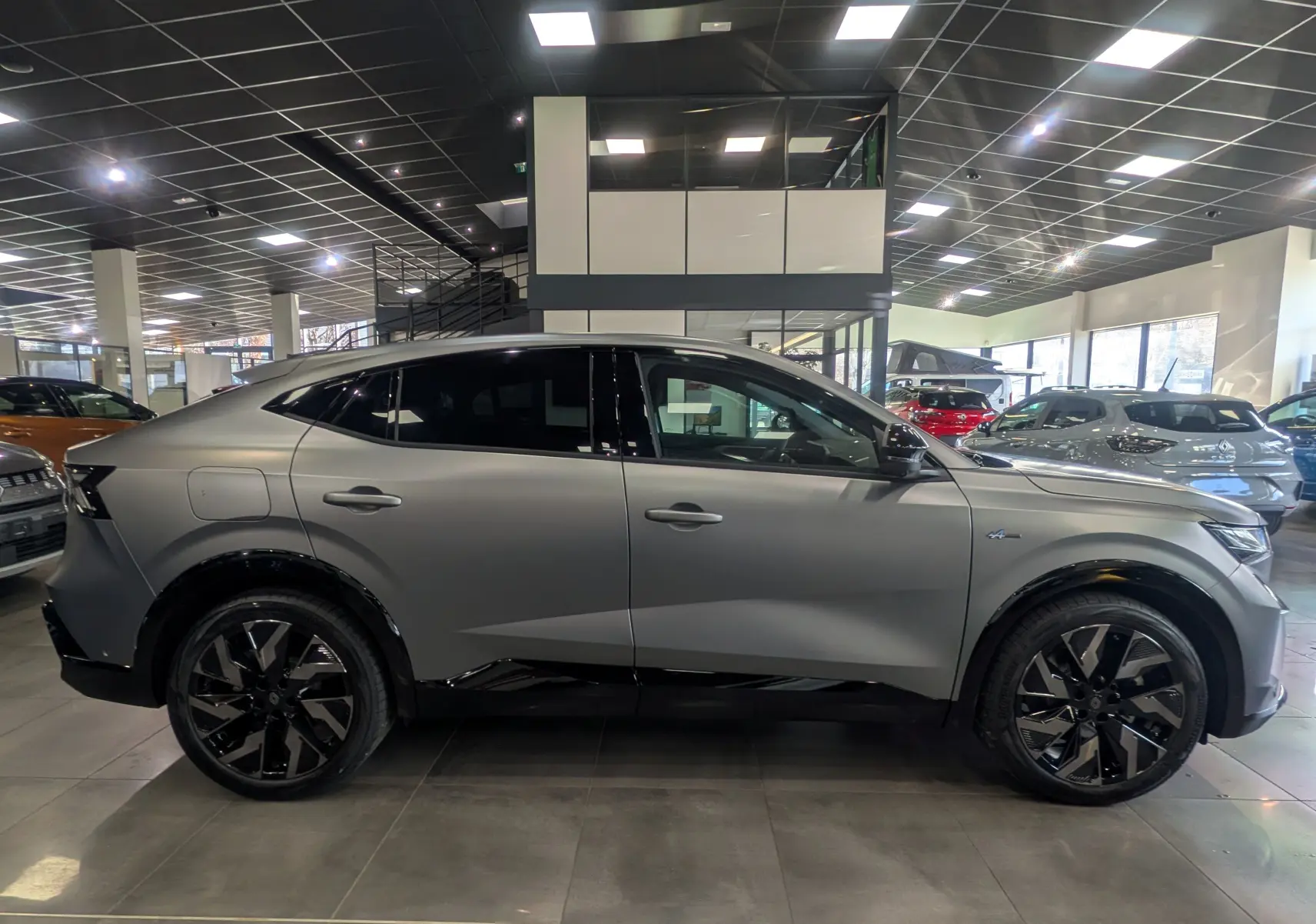 Vue latérale droite d'une Renault Rafale E-TECH gris schiste satin avec jantes noires et toit noir en concession.
