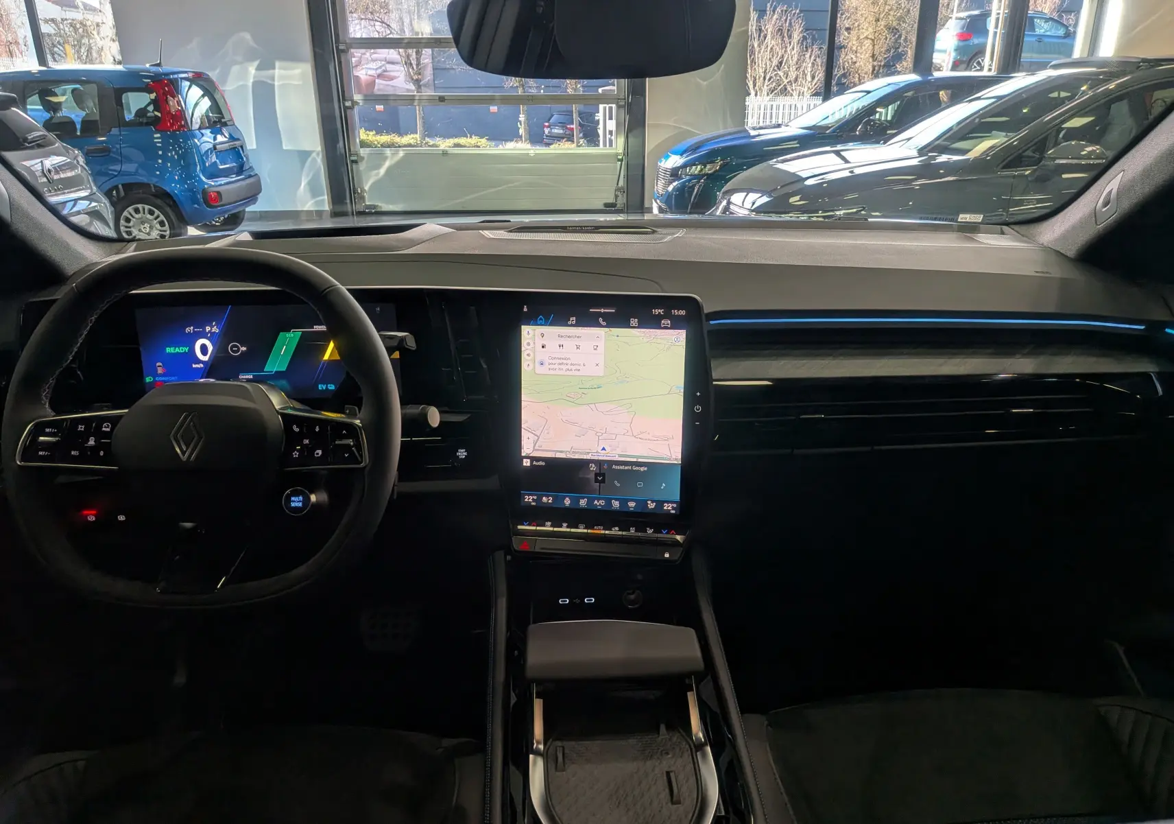 Vue intérieure frontale du tableau de bord du Renault Rafale E-TECH 2025, avec écran tactile vertical et éclairage d'ambiance bleu.