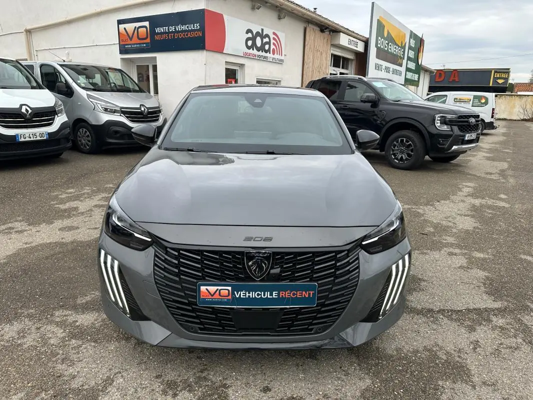 Vue de face d'une Peugeot 208 gris 2025 avec calandre noire et feux LED verticaux distinctifs, stationnée en extérieur.