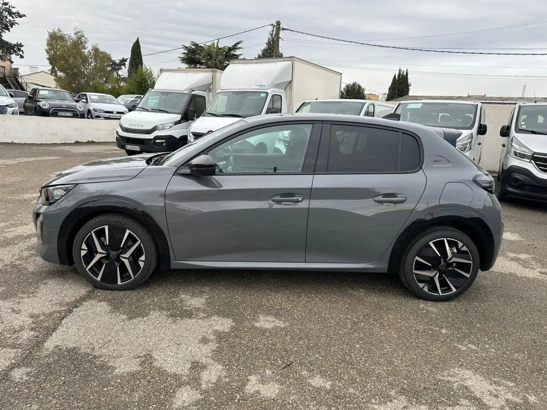 Profil droit d'une Peugeot 208 Hybrid 110 e-DCS6 GT gris, avec jantes alliage 17 pouces et toit noir.