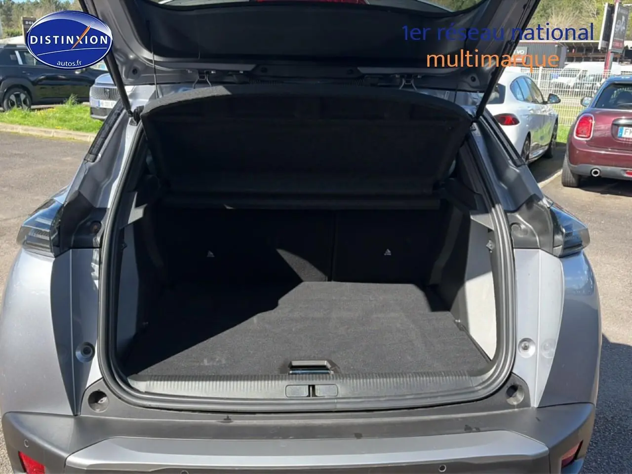 Coffre ouvert d'un Peugeot 2008 gris artense vu de l'arrière, montrant l'espace de chargement vide.