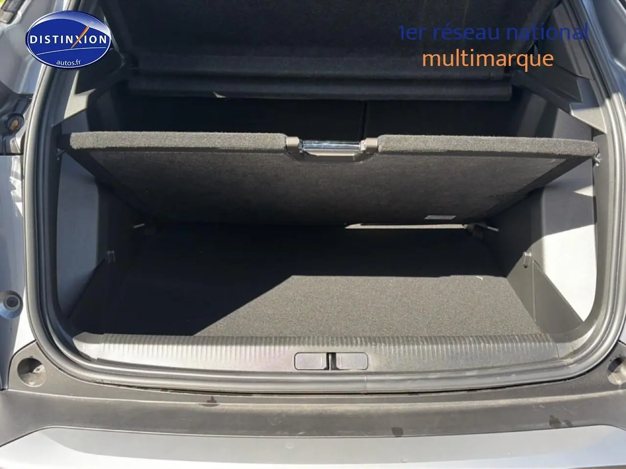 Coffre ouvert vu de l'arrière d'un Peugeot 2008 gris artense avec cache-bagages partiellement relevé.