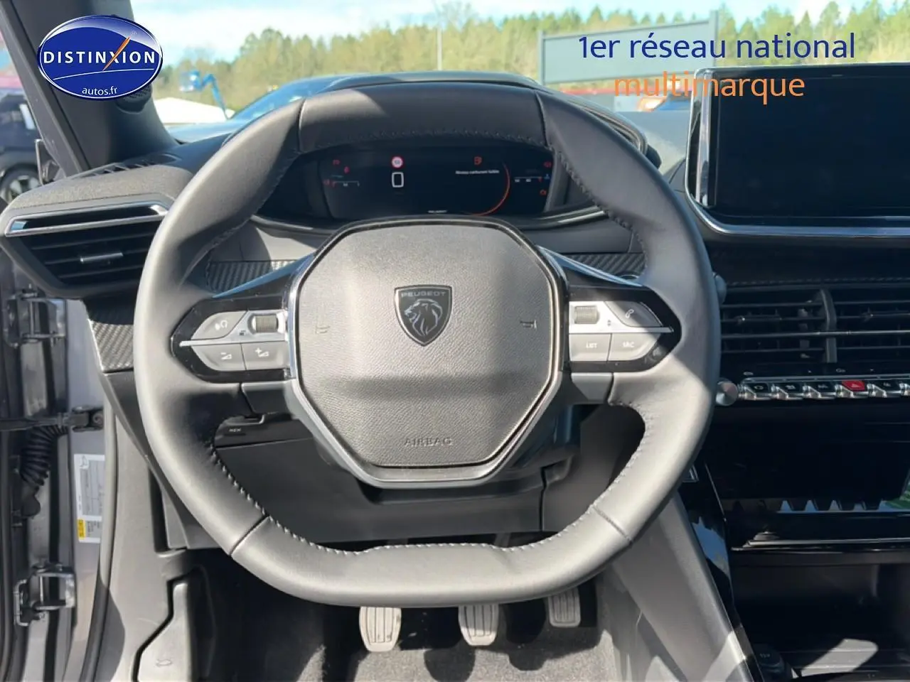 Vue rapprochée du volant multifonction noir de la Peugeot 2008 2025 avec tableau de bord numérique en arrière-plan.