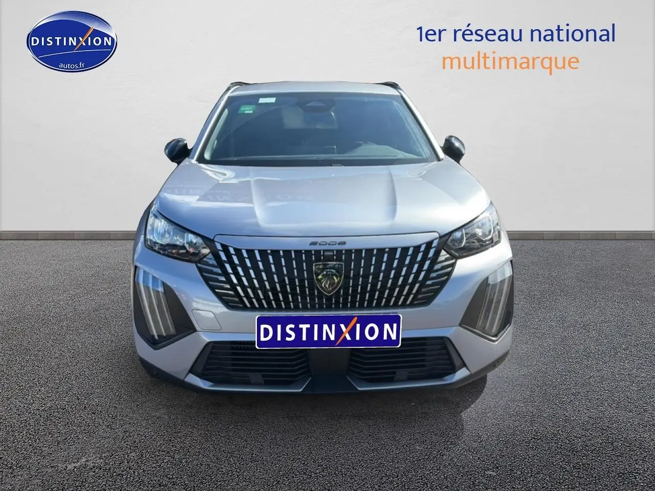 Vue frontale d'un Peugeot 2008 gris artense avec calandre verticale distinctive et phares LED allumés.