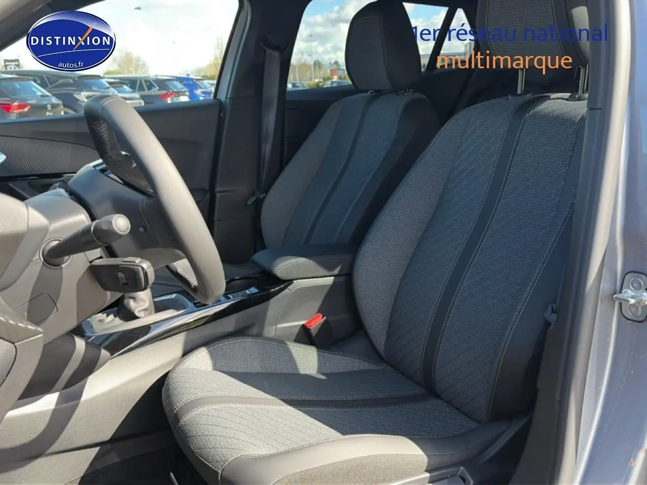 Vue intérieure côté conducteur du Peugeot 2008 1.2 100 allure gris artense, mettant en valeur les sièges tissu et la console centrale.