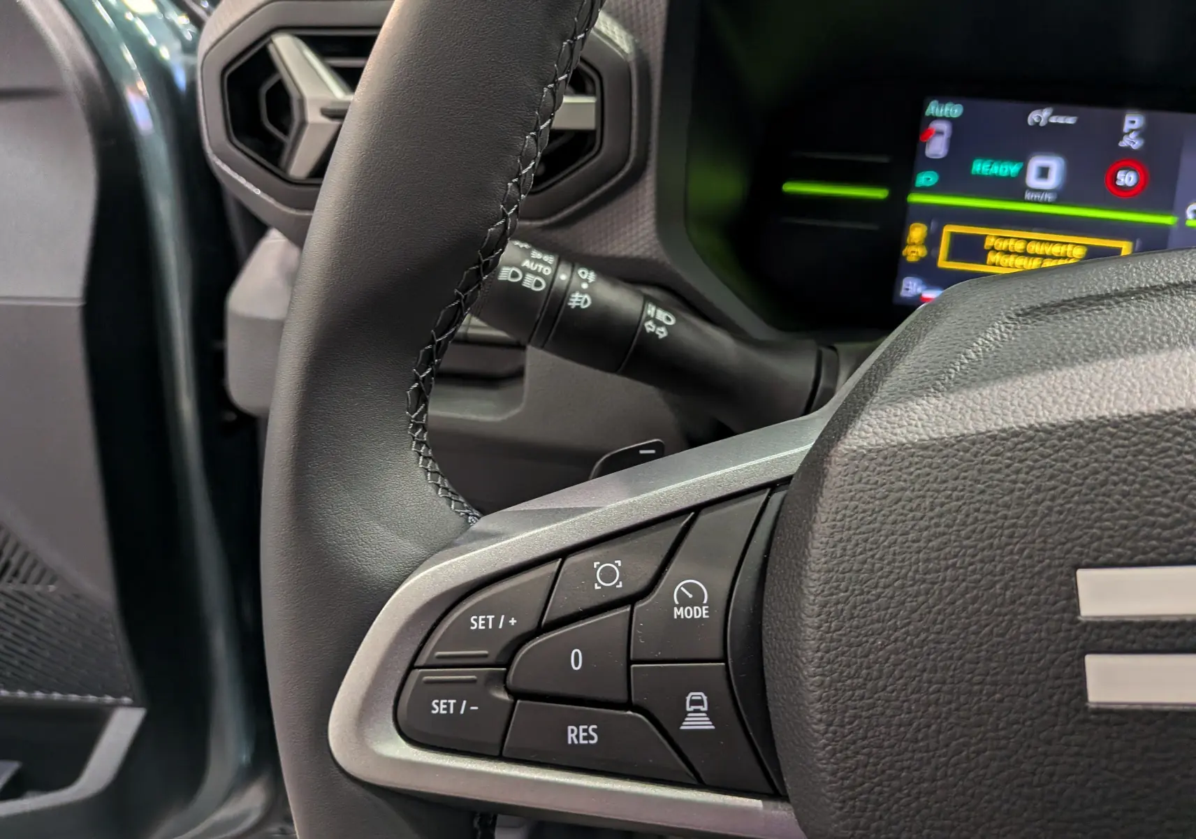 Gros plan sur le volant côté gauche du Dacia Duster Hybrid-G 150 CH 4x4 2026 avec commandes multifonctions et tableau de bord numérique.