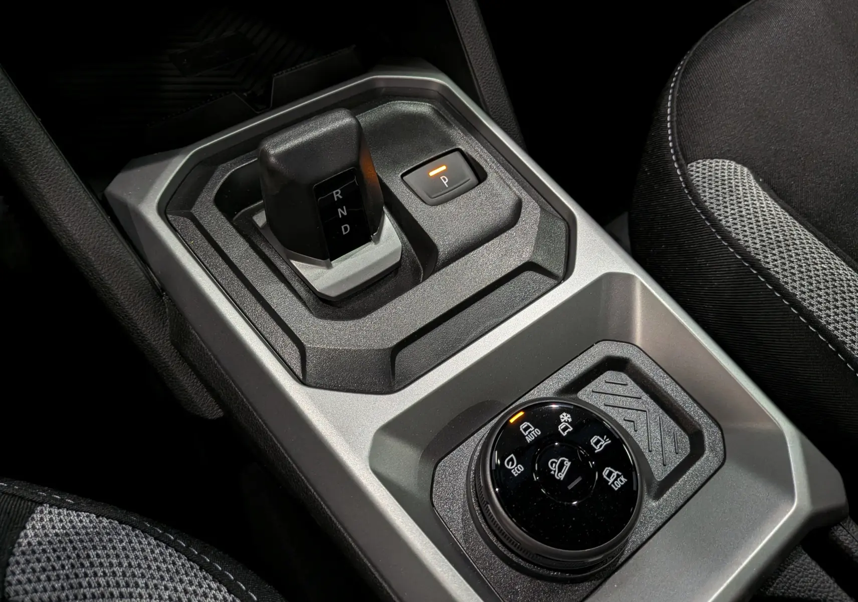 Gros plan sur la console centrale du Dacia Duster Hybrid-G 150 CH 4x4, montrant le levier de vitesse automatique et la molette de modes de conduite.