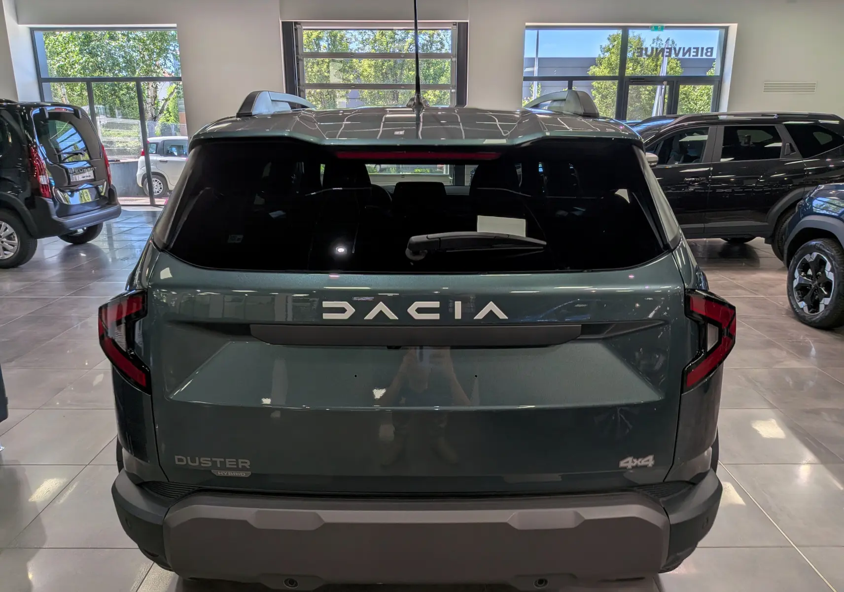 Vue arrière du Dacia Duster Hybrid-G 150 CH 4x4 en Vert Cèdre, avec logo DACIA et feux arrière en forme de C.