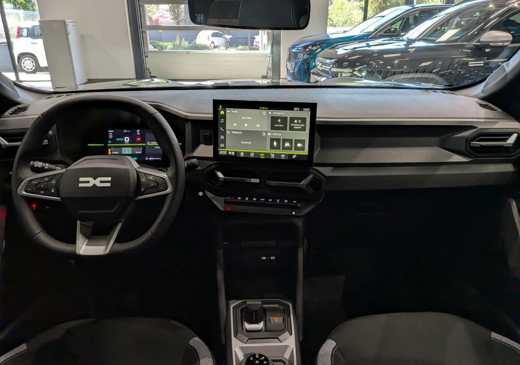 Vue intérieure avant du tableau de bord du Dacia Duster Hybrid-G 150 CH 4x4, avec écran tactile central et volant multifonction.