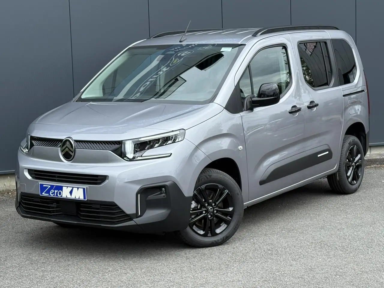 Citroën Berlingo Multispace gris acier en 3/4 avant droit avec jantes noires et barres de toit noires brillantes.