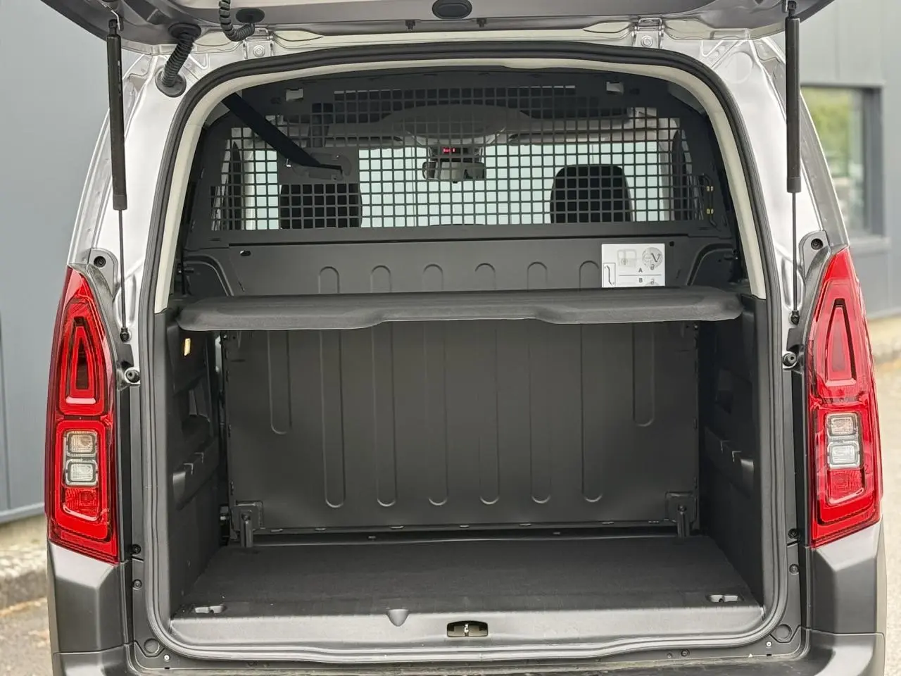 Coffre ouvert arrière d'un Citroën Berlingo Multispace gris acier, avec lunette arrière ouvrante et grille de séparation.
