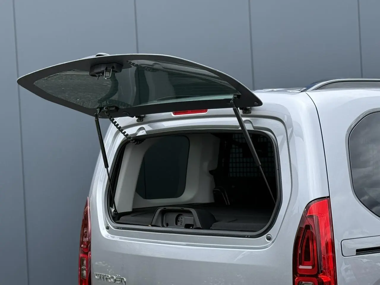 Vue arrière du Citroën Berlingo gris acier 2026 avec lunette arrière ouvrante relevée et vitres surteintées.