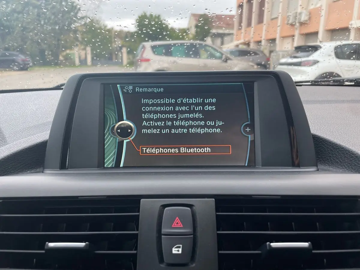 Écran central du tableau de bord de la BMW Série 2 Coupé F22 blanc, affichant un message Bluetooth sous la pluie.