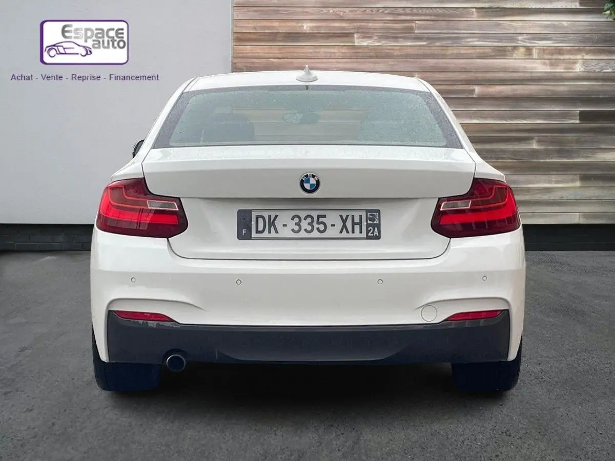 Vue arrière d'une BMW Série 2 Coupé F22 blanche, version 220d M Sport, avec feux rouges et échappement visible côté gauche.