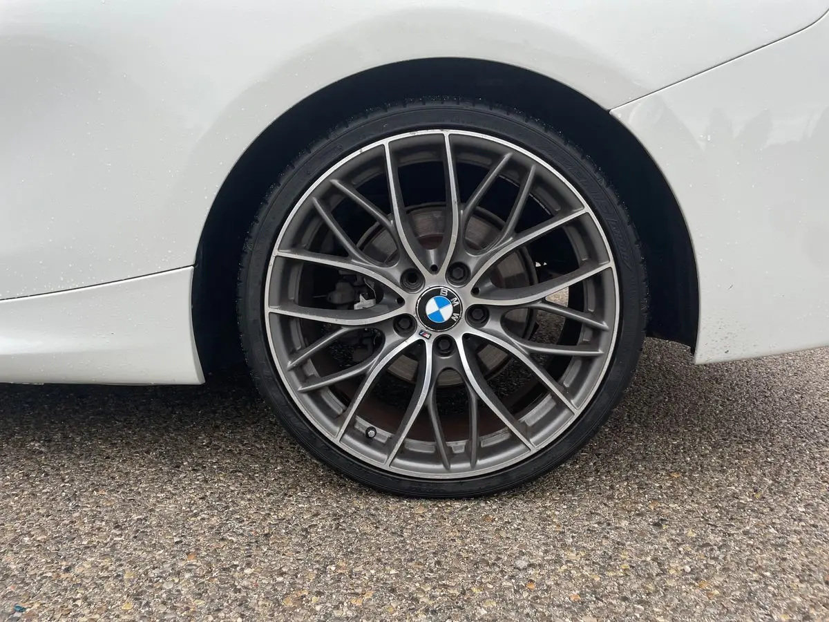 Gros plan sur la roue arrière droite d'une BMW Série 2 Coupé F22 blanche avec jante alliage M Sport multibranches.